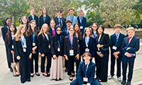  A group of business students wearing suits smile for a photo.